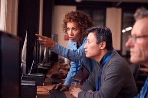 IT Support Personnel working with older employee to resolve technical issues.